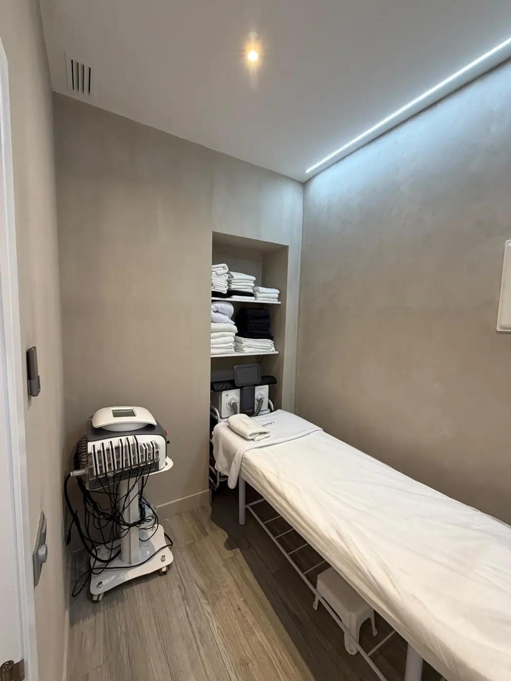 La cabina terminada, con el acabado de pared, baldas con toallas y camilla